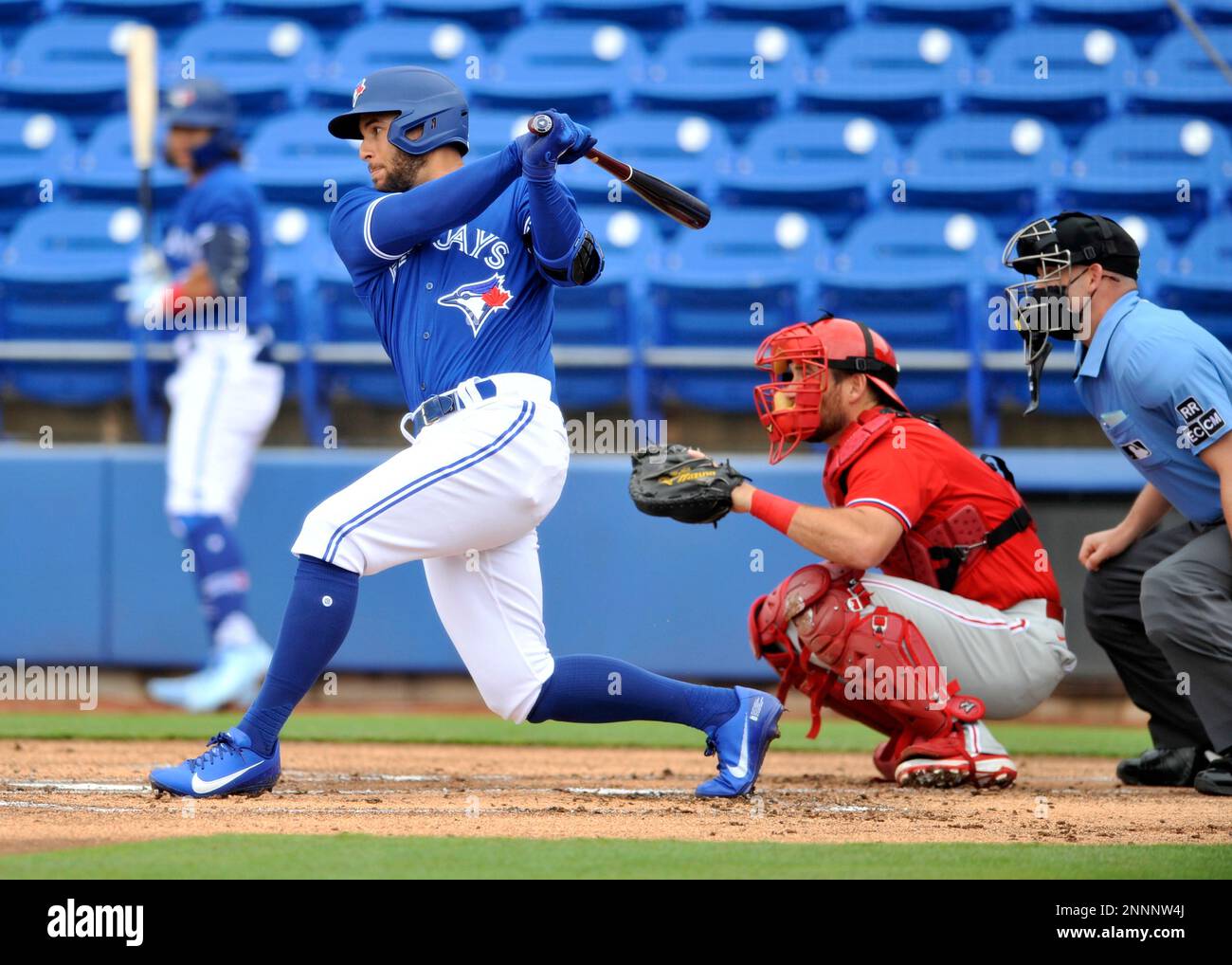 Philadelphia Phillies catcher Jeff Mathis, center, looks on as Toronto Blue Jays' George Springer hits a single during the first inning of a spring training baseball game in Dunedin, Fla., Saturday, March 6, 2021. (Steve Nesius/The Canadian Press via AP) Stockfoto