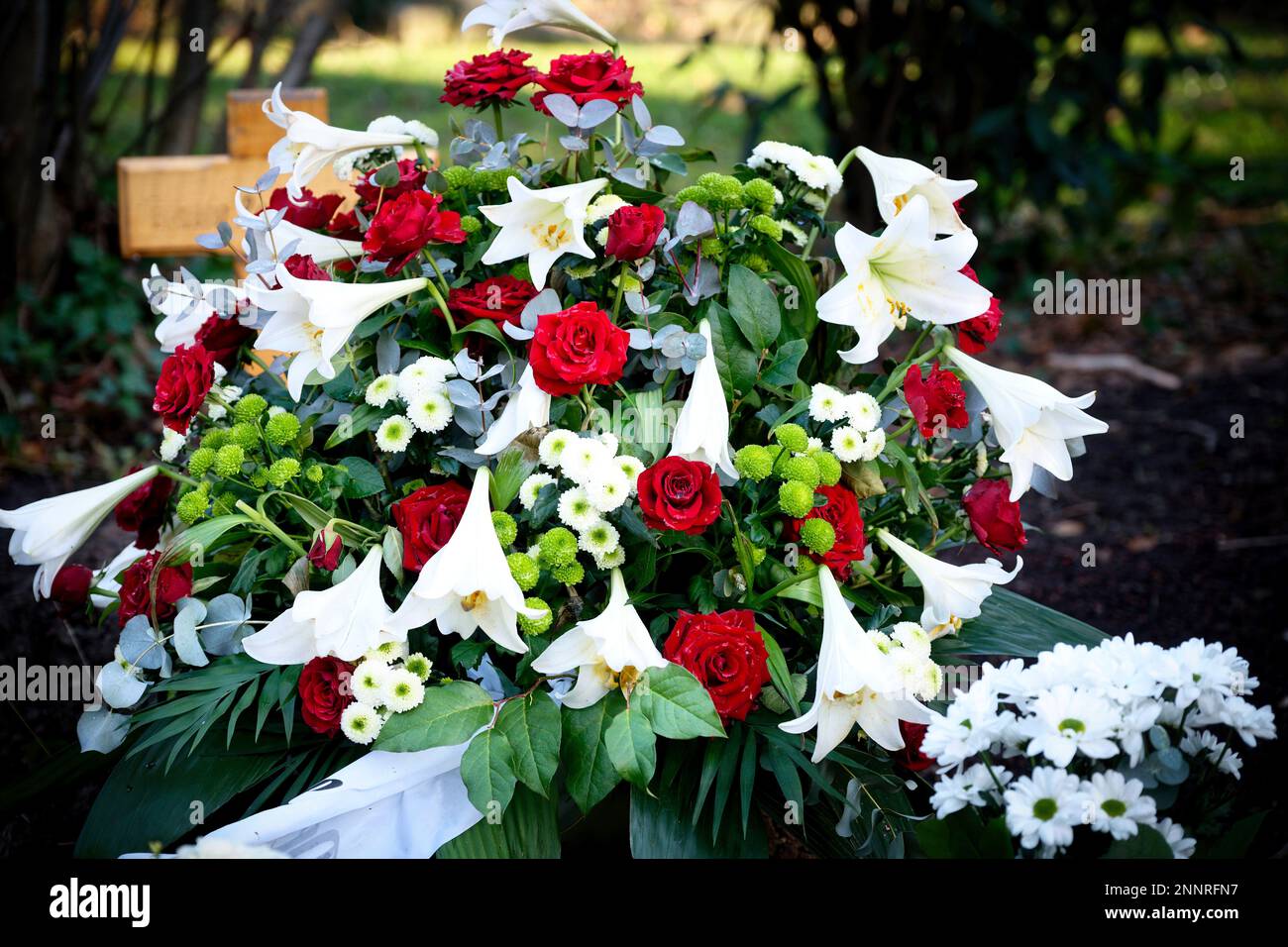 Rote Rosen und weiße Lilien auf einem Grab nach einer Beerdigung Stockfoto