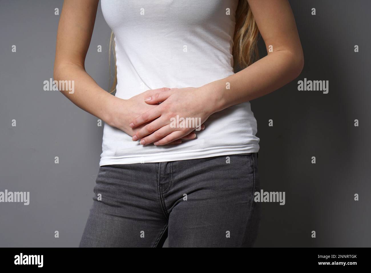Unerkannte junge Frau, die ihren Magen mit beiden Händen hält - Konzept für Dysmenorrhoe, Bauchschmerzen, Reizdarmsyndrom, Bauch oder Magen Stockfoto