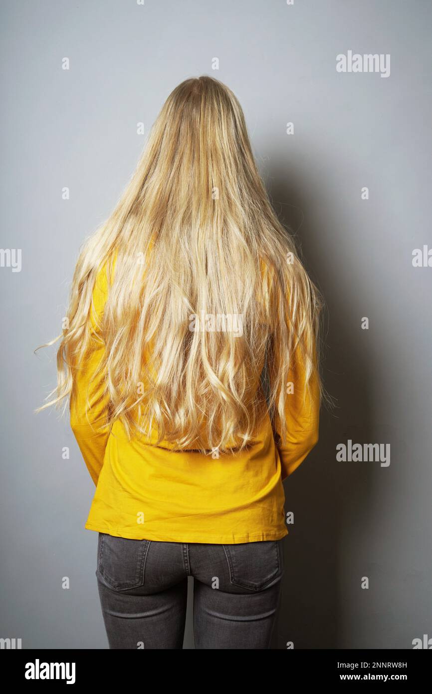 Ansicht der Rückseite des junge Frau mit langen blonden Haaren steht dabei mit dem Gesicht an der Wand Stockfoto