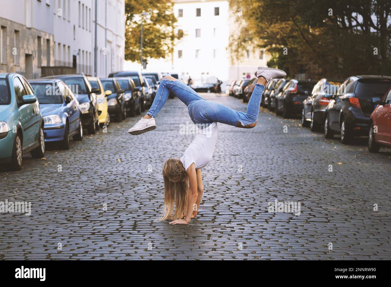 Unbeschwerte junge Frau dabei spontane Handstand in der Mitte der Stadt. Stockfoto