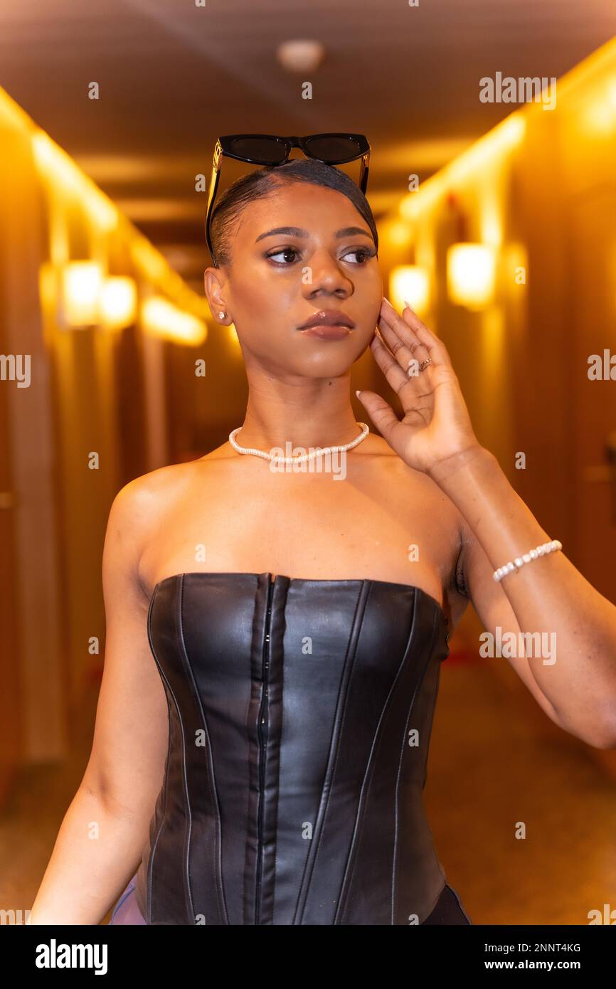 Mittelgroße Aufnahme einer reichen schwarzen ethnischen Frau, die sich im Hotelzimmerflur posiert, Luxuskonzept Stockfoto