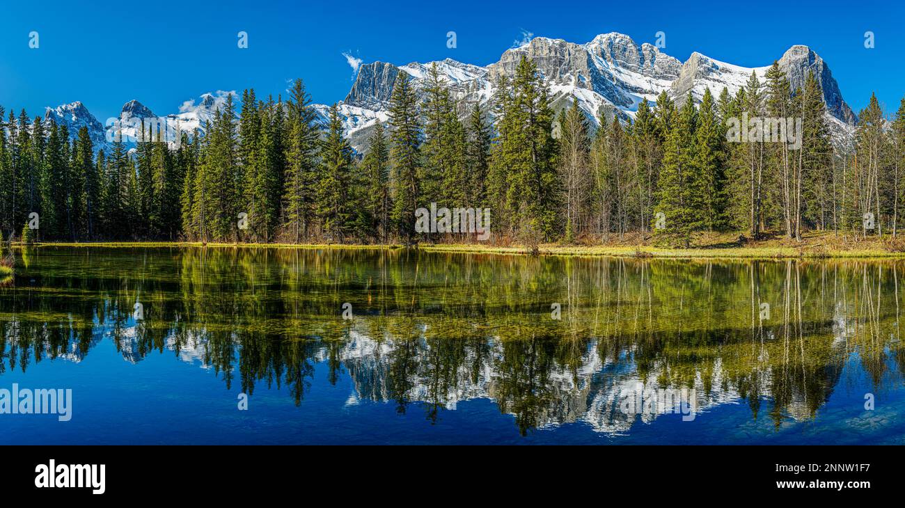 Die Bergkette spiegelt sich im Spring Creek Pond in Canmore, Alberta, Kanada, wider Stockfoto