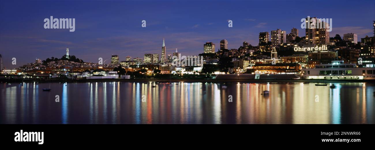 Boote vor dem beleuchteten Ghiradelli Square und umliegenden Gebäuden bei Nacht, San Francisco, Kalifornien, USA Stockfoto