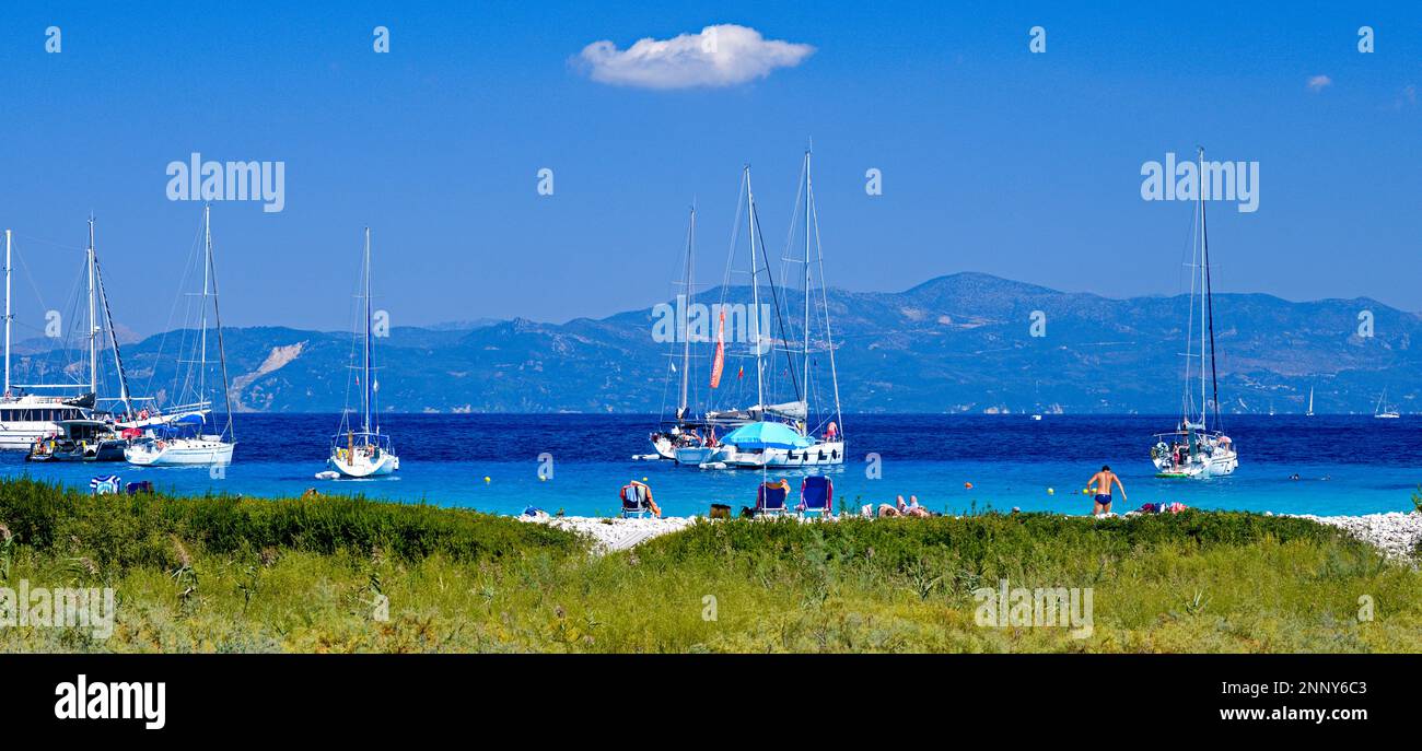Touristen am Strand und Segelboote in Lakka Bay, Paxos, Ionischen Inseln, Griechenland Stockfoto