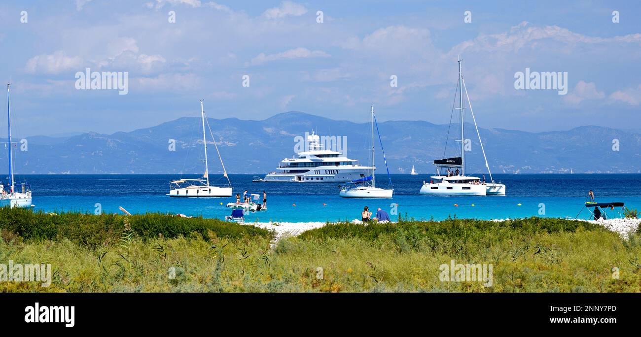 Touristen am Strand und Segelboote in Lakka Bay, Paxos, Ionischen Inseln, Griechenland Stockfoto