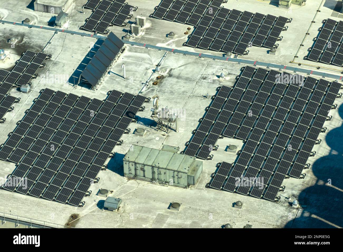 Luftaufnahme eines Solarkraftwerks mit blauen Photovoltaik-Paneelen, die auf dem Dach eines Industriegebäudes montiert sind, um ökologischen Ökostrom zu erzeugen. Produkt Stockfoto