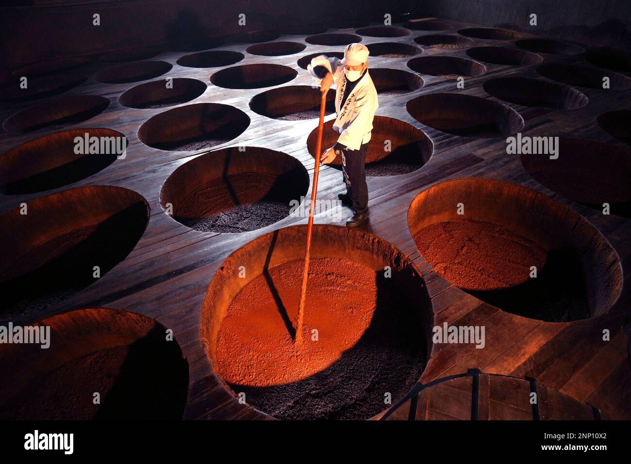 A photo shows a scene of making Japanese soy sauce (shoyu) at a factory in Kurume City, Fukuoka Prefecture, western Japan, on January 26, 2021. A staff agitates unrefined soy sauce with a bamboo stick. Soy sauce (soya sauce) is one of the basic seasonings in Japanese cuisine and a liquid condiment of Chinese origin, traditionally made from a fermented paste of soybeans, roasted grain, brine, and Aspergillus oryzae or Aspergillus sojae molds. ( The Yomiuri Shimbun via AP Images ) Stockfoto