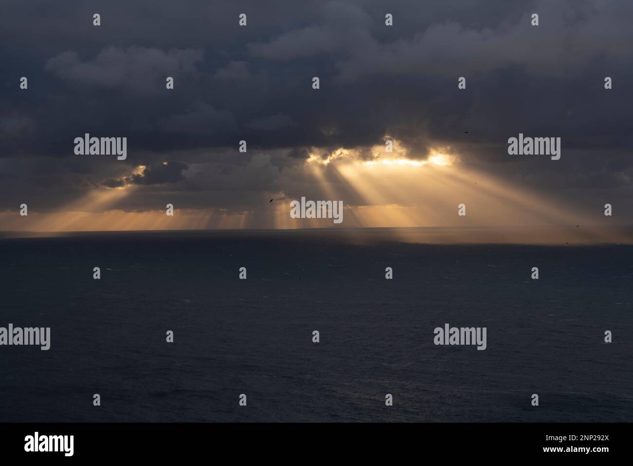 Die Sonne strahlt von den Wolken über dem Meer Stockfoto