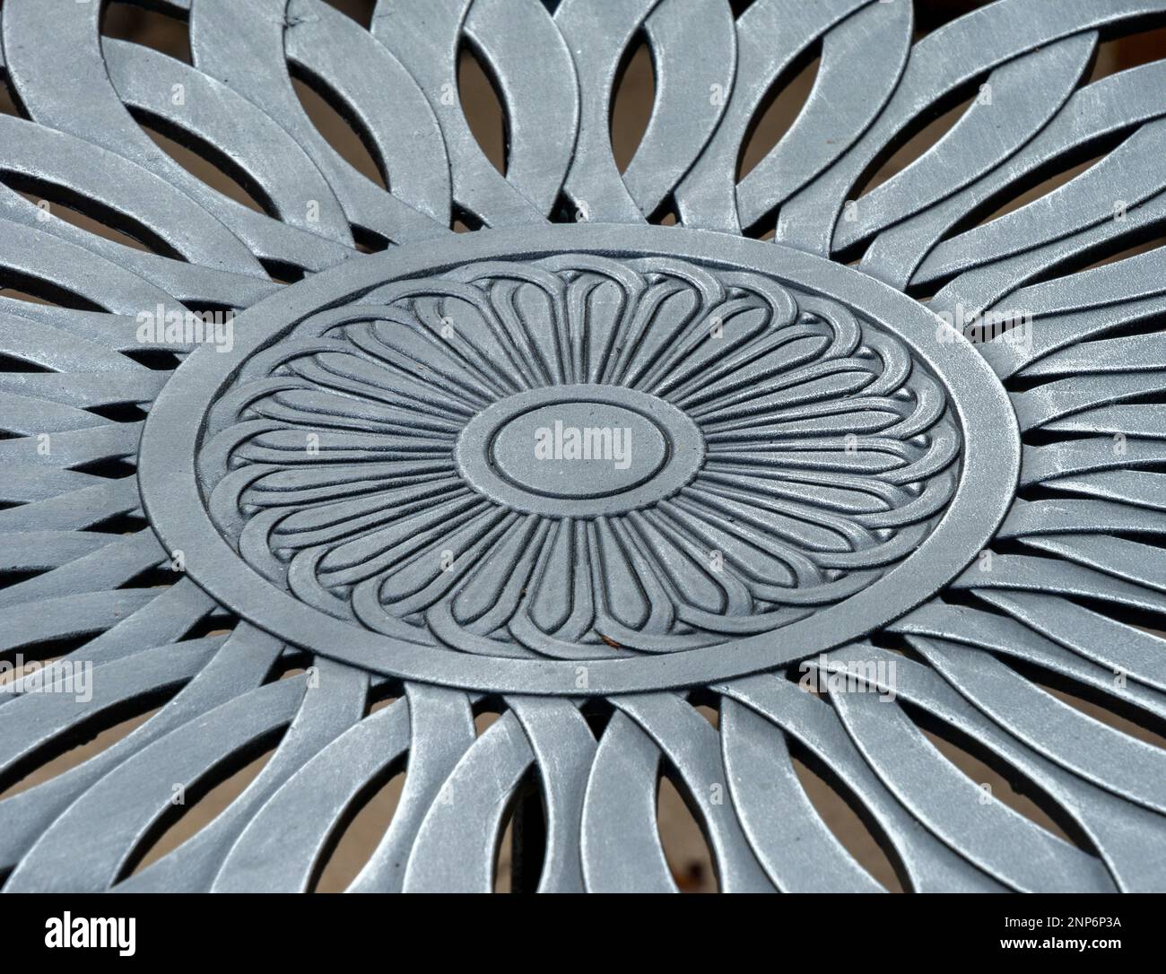 Nahaufnahme mit Details des Blumenmusters in der Gartentischplatte aus Aluminiumguss. Stockfoto