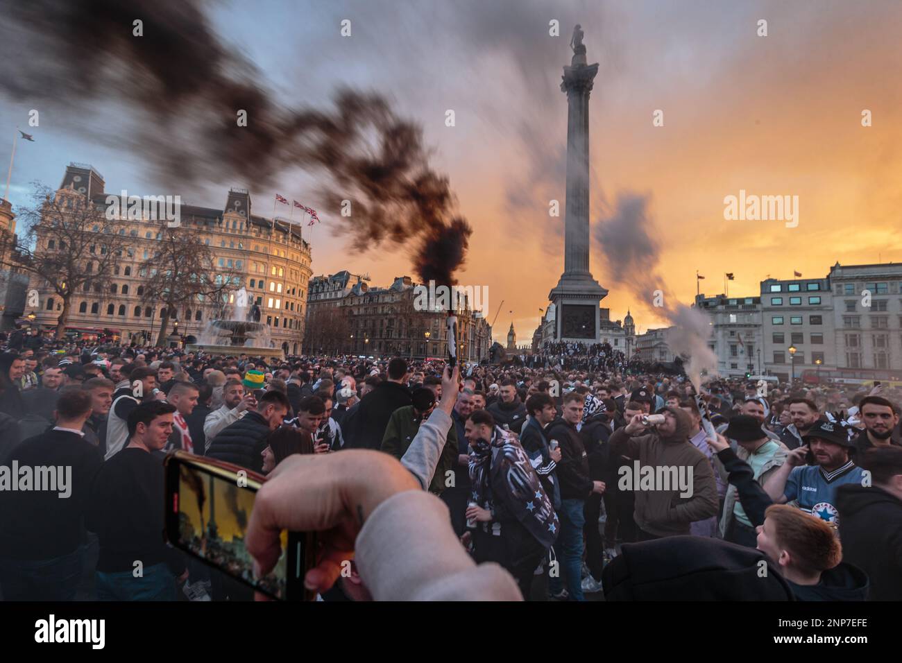 Schwarzer und weißer Rauch bei Sonnenuntergang, während die Fans von Newcastle United den Trafalgar Square vor dem Carabao Cup-Finale gegen Manchester United übernehmen. Stockfoto