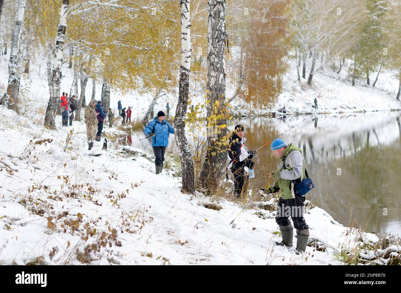 Die Menschen sind Fischer an beiden schneebedeckten Ufern des Sees bei der Konkurrenz in Russland im Wald Stockfoto