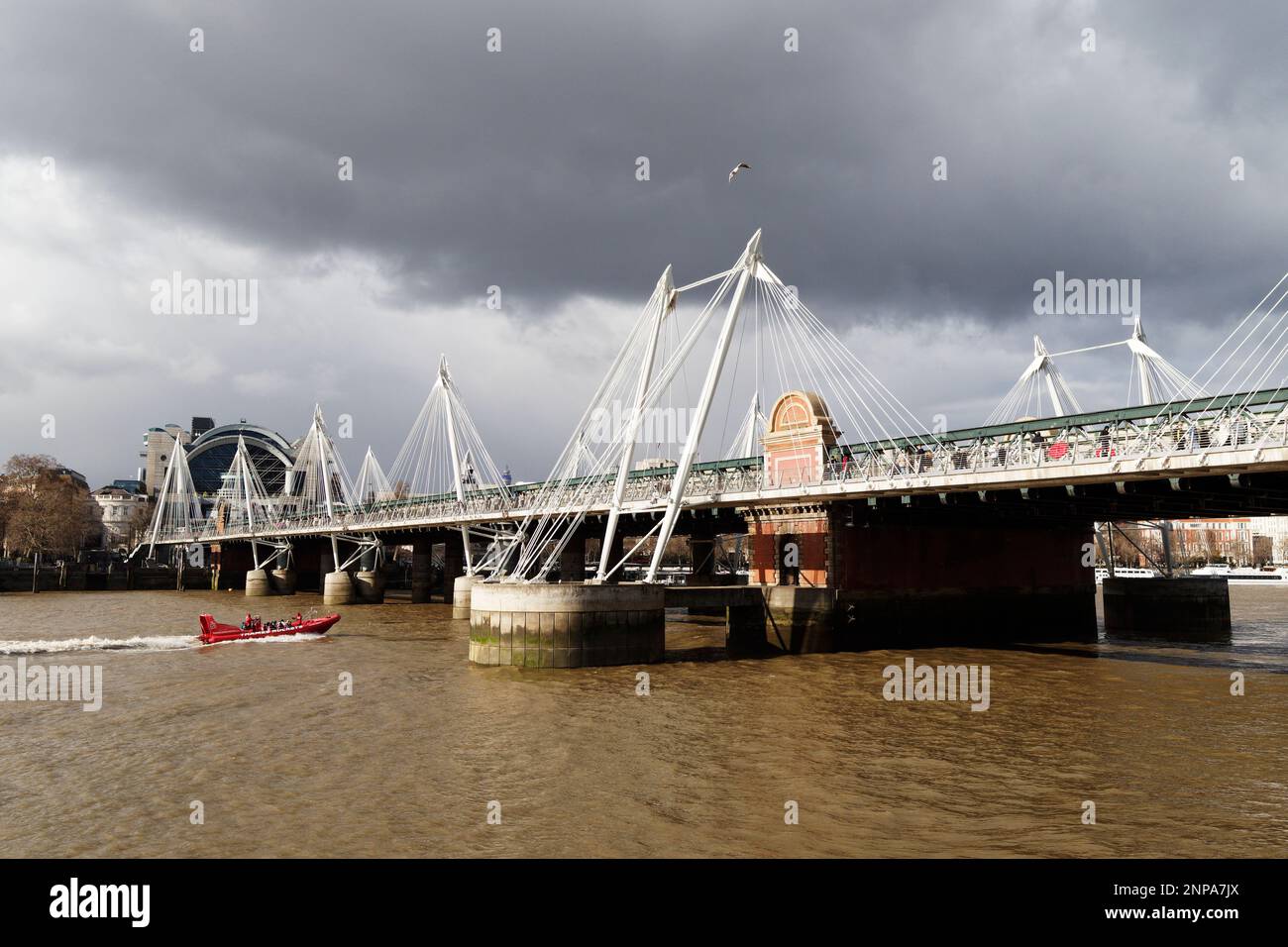 Rotes Dingy-Boot auf der Themse neben Jubilee-Brücken mit dem Bahnhof Charing Cross, London, England Stockfoto