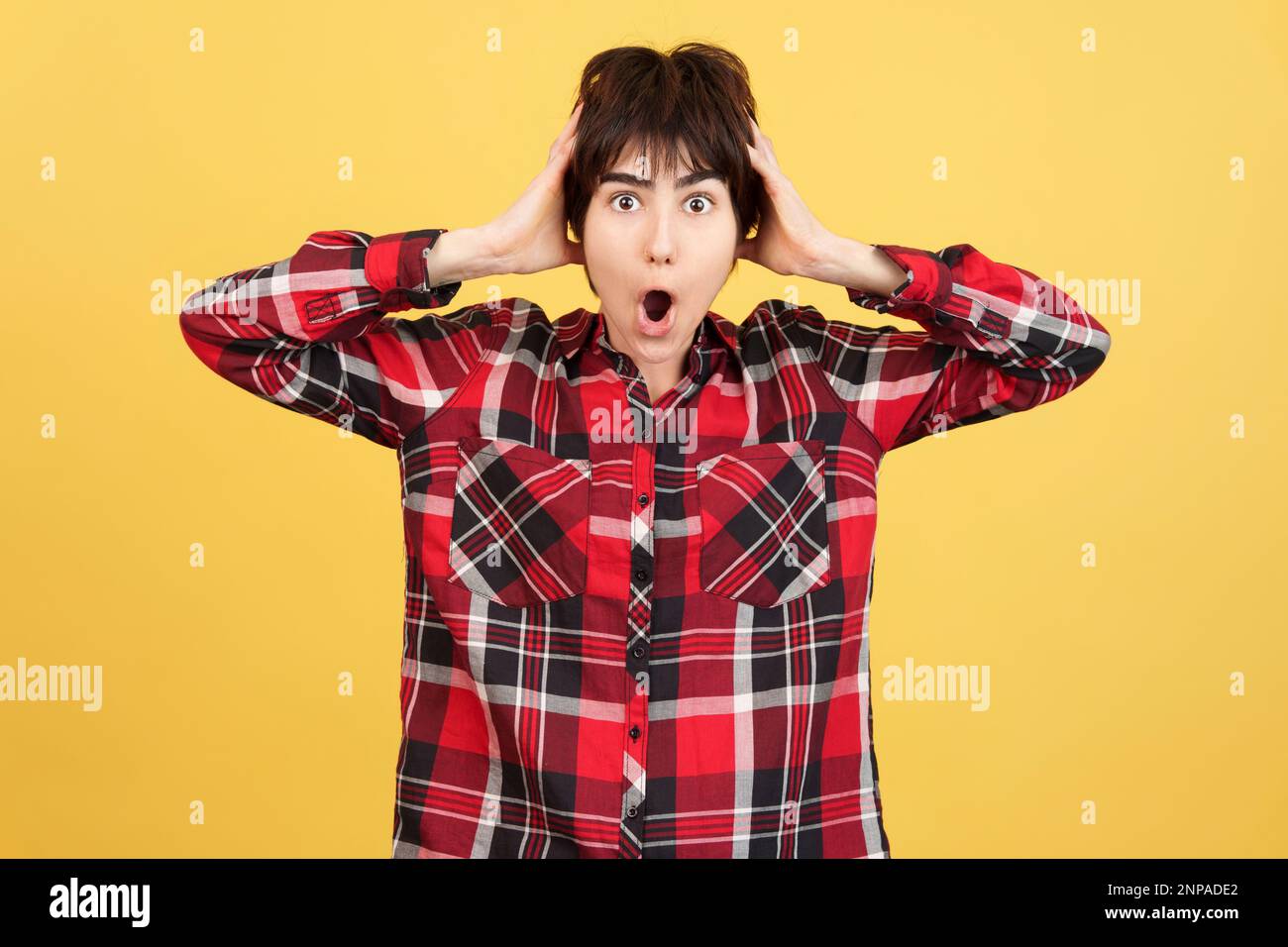 Androgyne Person, die in die Kamera schaut, während sie Überraschung ausdrückt Stockfoto