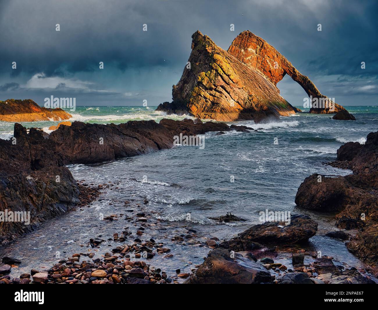 Am Tag nach dem Sturm Otto, der mit 100mph Winden den den Nordosten Schottlands erreichte, erstrahlt ein Sonnenschein auf dem Bowfiddle Rock. Der Sturm geht in seine Tiefe Stockfoto