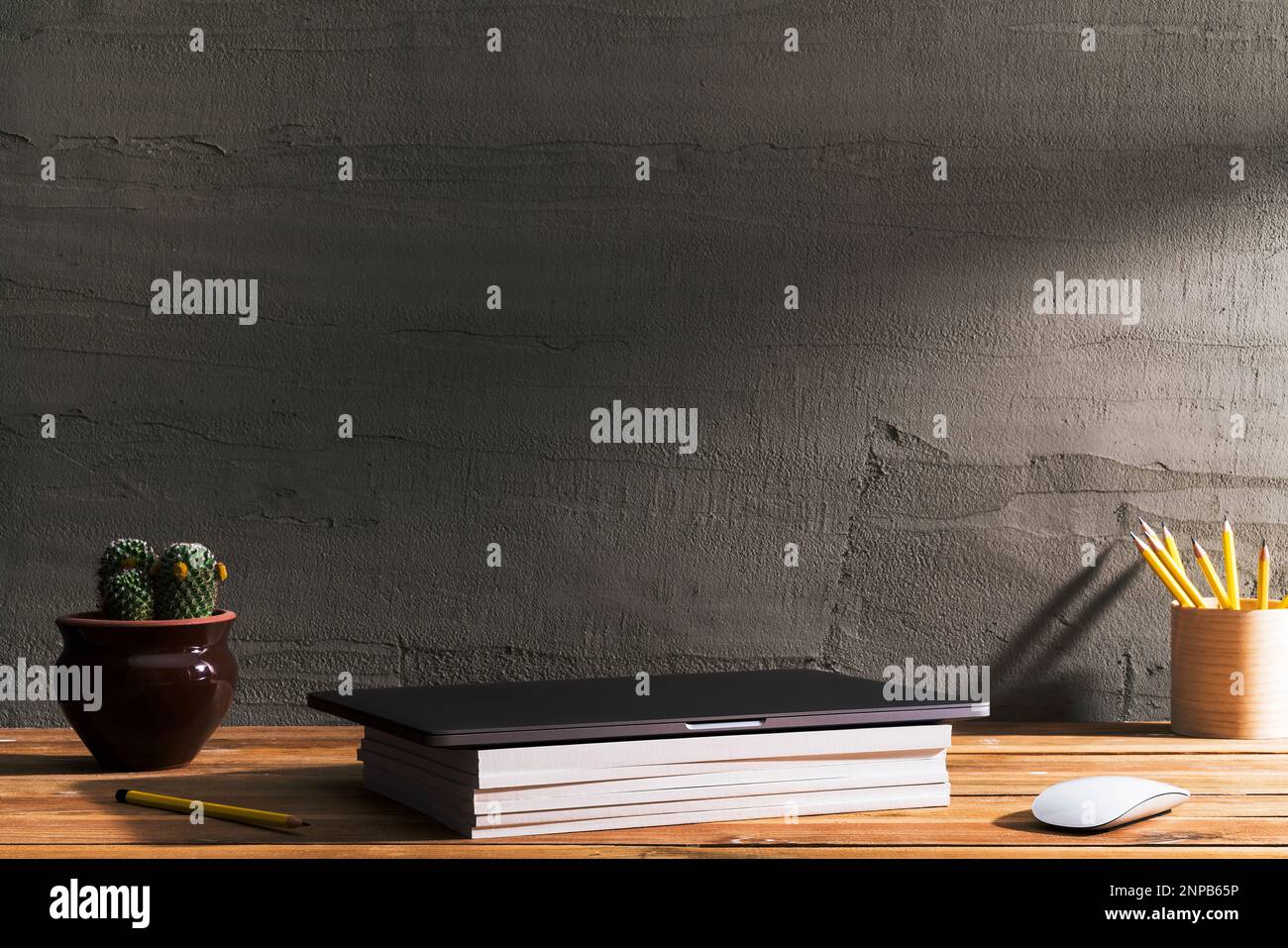 Geschlossener Laptop mit weißem Magazinstapel auf dem Tisch. Tischaufnahme des Innenraums mit Fensterlichteffekt. Stockfoto