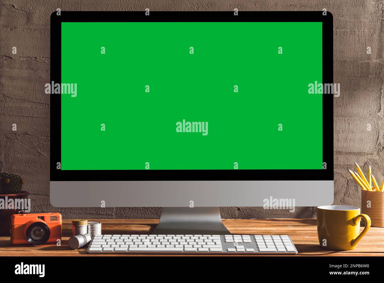 Chroma Key Green Screen Computer mit Fotoausrüstung auf dem Tisch. Tischaufnahme des Innenraums mit Fensterlichteffekt. Stockfoto