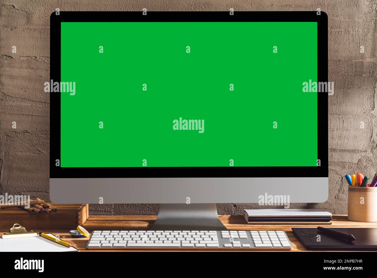 Chroma Key Green Screen Computer, Desktop pc auf dem Tisch des Designers. Tischaufnahme des Innenraums mit Fensterlichteffekt. Stockfoto