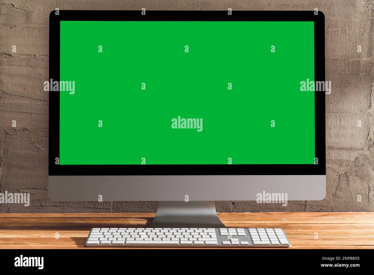 Chroma-Schlüssel mit grünem Bildschirm, Desktop-pc auf dem Tisch. Tischaufnahme des Innenraums mit Fensterlichteffekt. Stockfoto