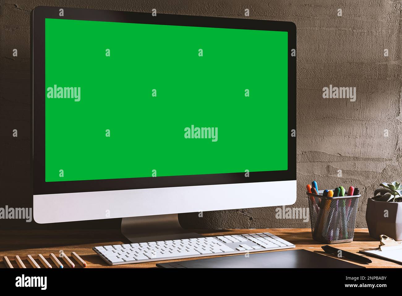 Chroma Key Green Screen Computer auf dem Tisch mit kreativen Werkzeugen zum Zeichnen und Zeichnen. Tabelle des Designers. Tischaufnahme des Innenraums mit w Stockfoto