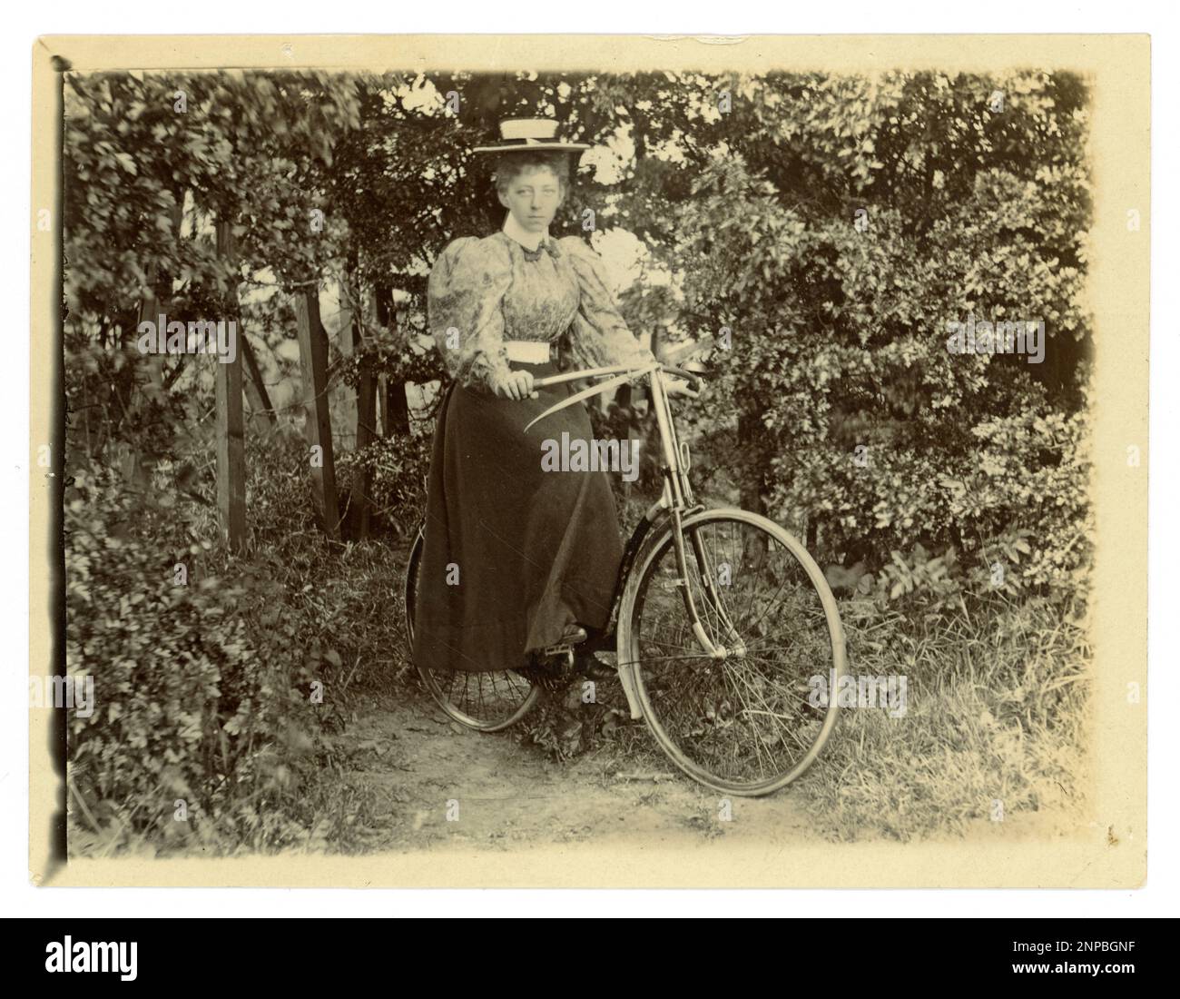Originales viktorianisches Foto einer Frau mit ihrem Fahrrad in einem Garten, Oldtimer-Radfahren, um 1898, Großbritannien Stockfoto