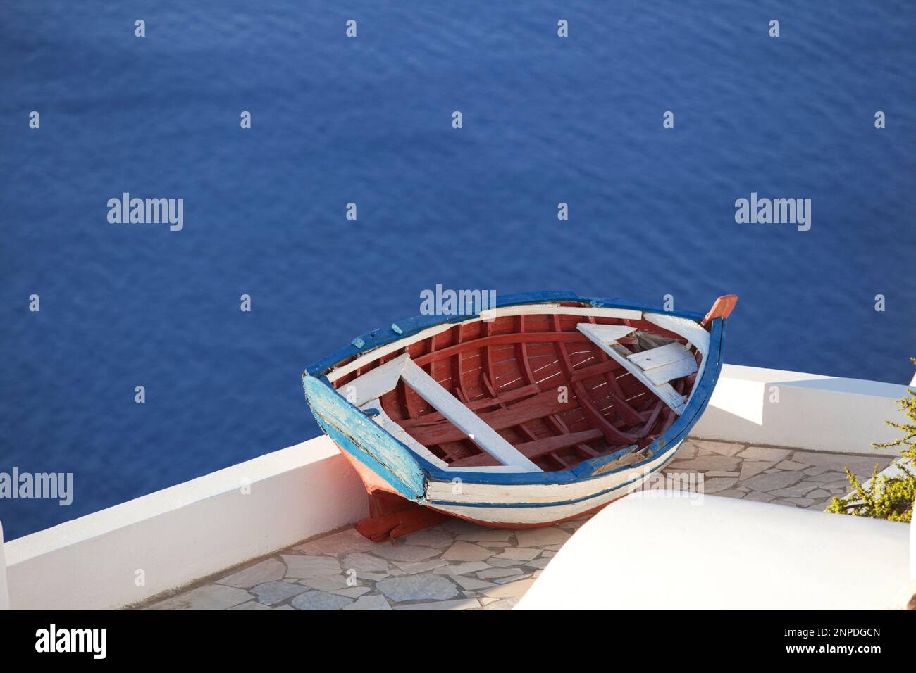 Ein traditionelles altes Fischerboot hoch oben auf einem Dach über dem Meer in Oia. Stockfoto