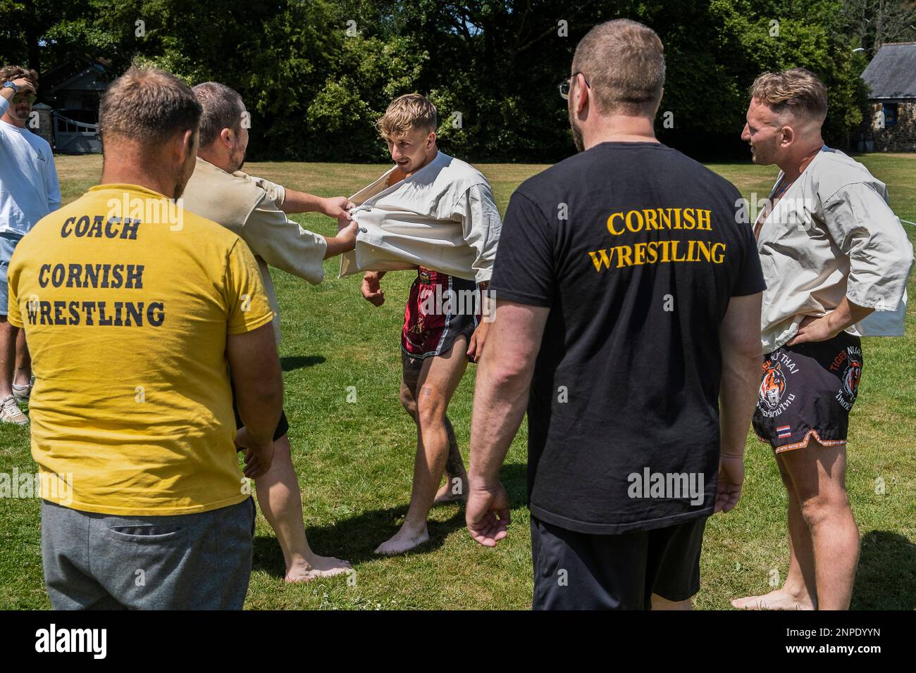 Trainer unterrichten die Regeln und Techniken des Cornish Wrestling vor dem Start des Grand Cornish Wrestling Tournament im malerischen Grün des Dorfes St. Mawgan in Pydar in Cornwall, England. Stockfoto