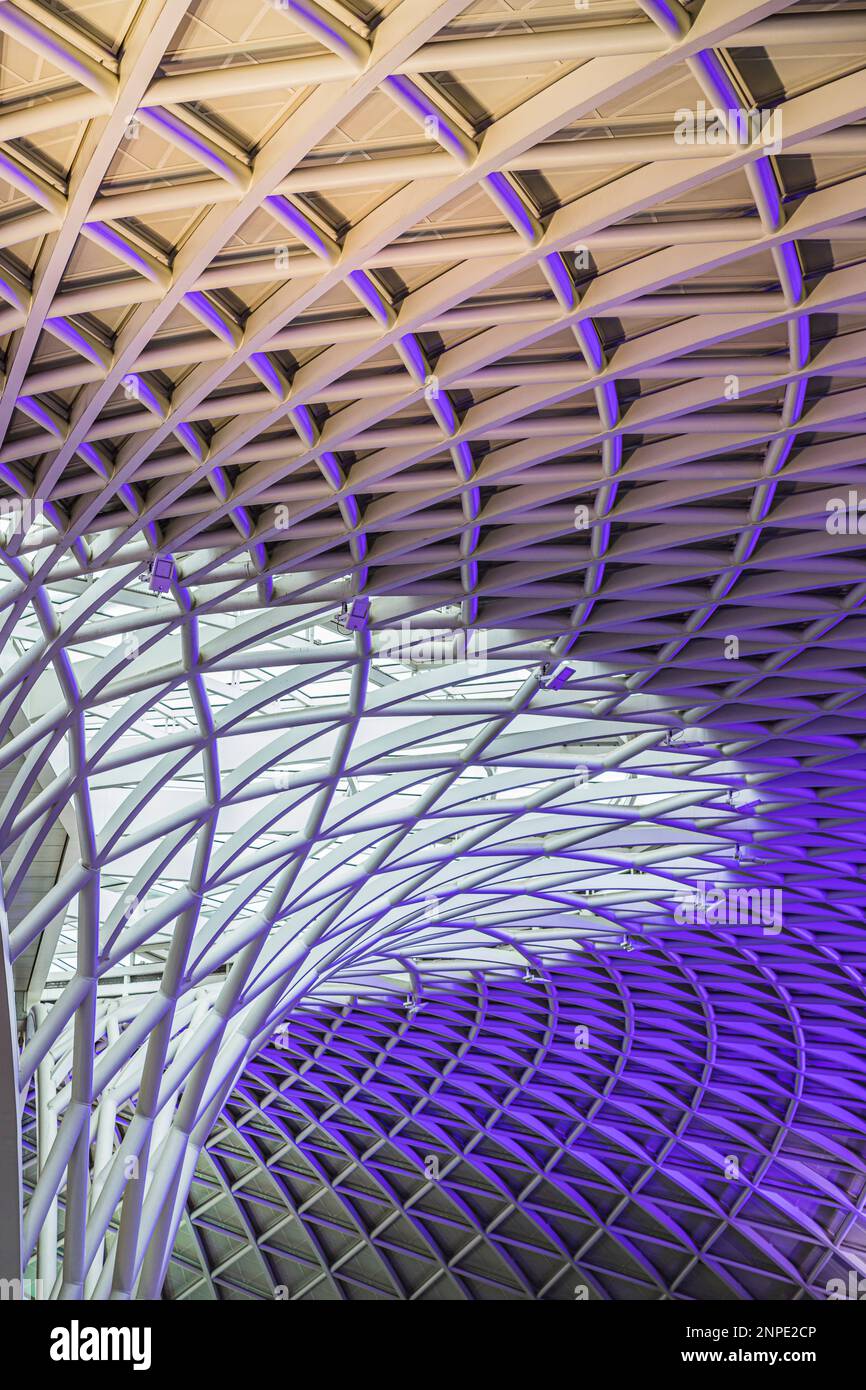 Eine Nahaufnahme der abstrakten Decke über dem Bahnhof Kings Cross, der in lila Lichtern beleuchtet ist. Stockfoto