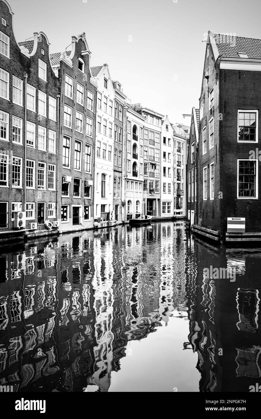 Alte Häuser am Kanal in Amsterdam, Niederlande. Schwarz-weiße Stadtlandschaft Stockfoto