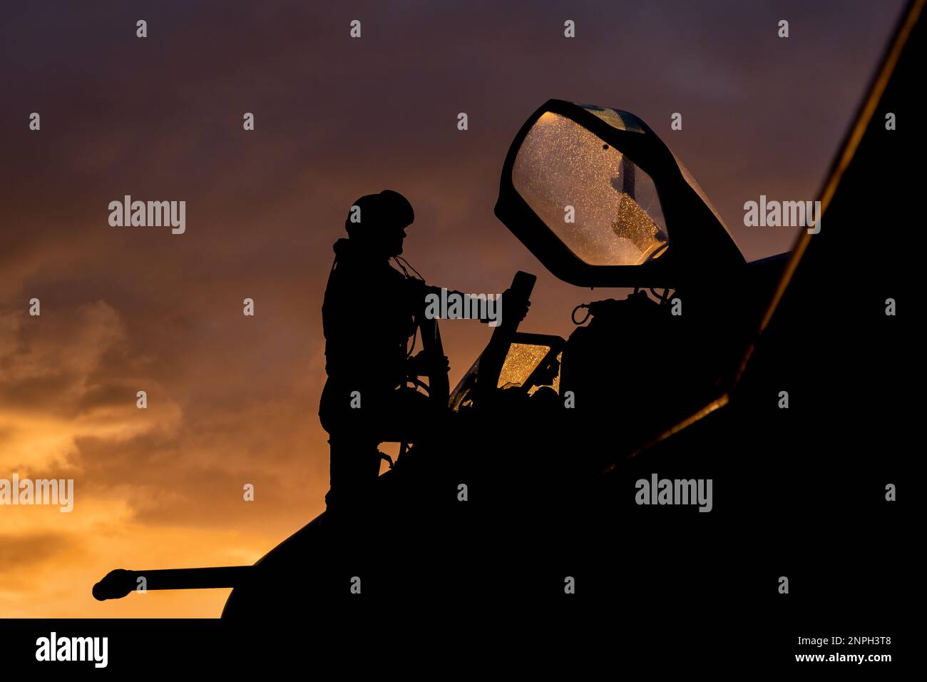 Der Kampfpilot steigt an Bord seines Abfangjägers für eine Kampftrainingsmission bei Sonnenuntergang. Dramatische Silhouette des Heldenpiloten, der sich auf den Krieg vorbereitet Stockfoto