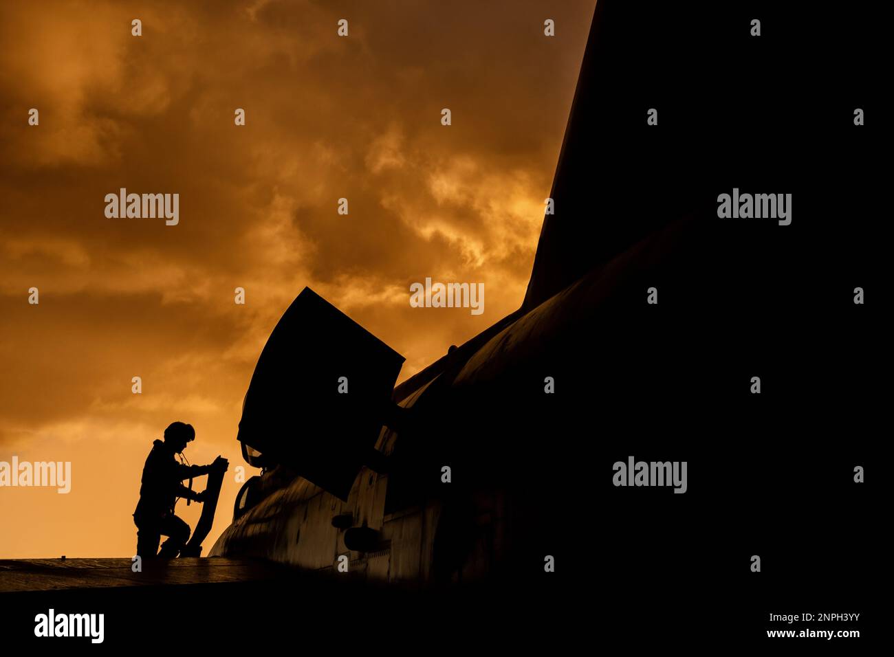 Der Kampfpilot steigt an Bord seines Abfangjägers für eine Kampftrainingsmission bei Sonnenuntergang. Dramatische Silhouette des Heldenpiloten, der sich auf den Krieg vorbereitet Stockfoto