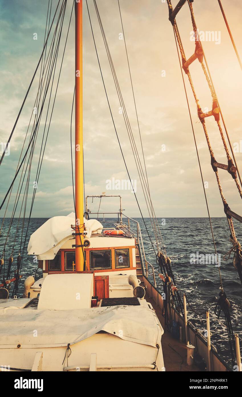 Alter Schoner segelt bei Sonnenuntergang, Farbtönung angewendet. Stockfoto