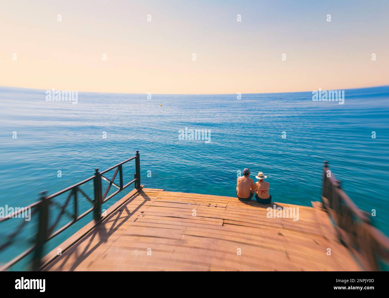 Marbella, Costa del Sol, Provinz Malaga, Andalusien, Südspanien. Ein Paar, das auf einem Holzpier sitzt. Stockfoto
