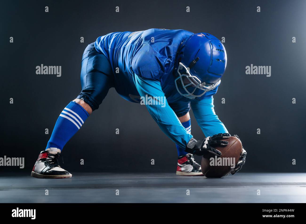 Ein amerikanischer Fußballspieler ist bereit, das Spiel auf schwarzem Hintergrund zu starten. Stockfoto