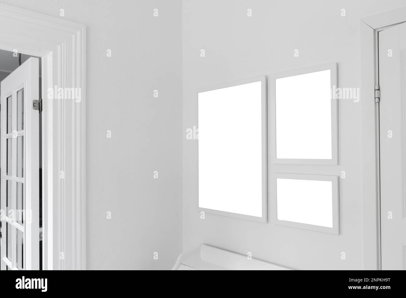 Drei weiße Holzbilderrahmen mit Mockup-Bereich für Fotos, die an der Wohnzimmerwand hängen, selektiver Fokus Stockfoto