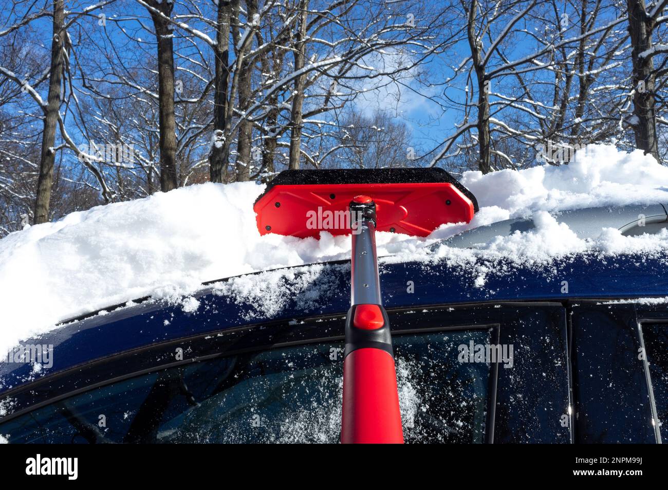 Den Schnee mit einer Bürste aus dem Auto entfernen Stockfoto