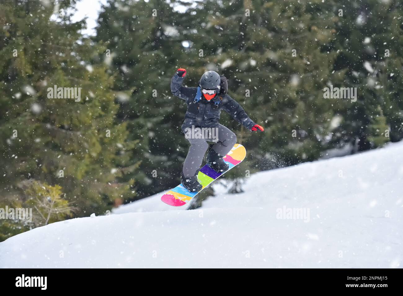 Extreme Sports Action: Snowboarder, die auf einem Hillside Jump durch die Luft fliegen Stockfoto