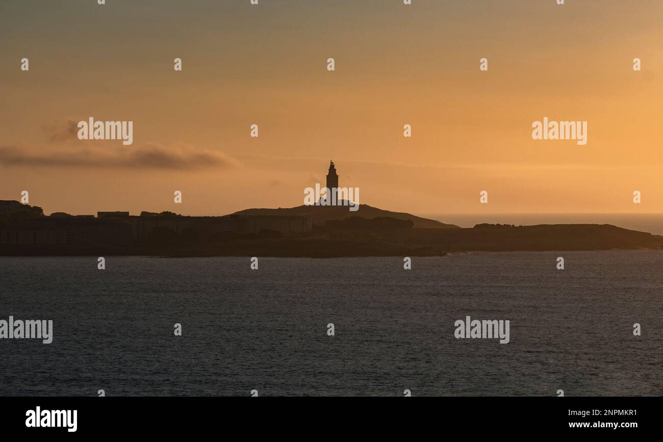 Turm des Herkules am Horizont, beleuchtet von den letzten Sonnenstrahlen bei Sonnenuntergang. Gelegen in Einem Coruña, Galicien, und von historischem Interesse, Kopie s Stockfoto