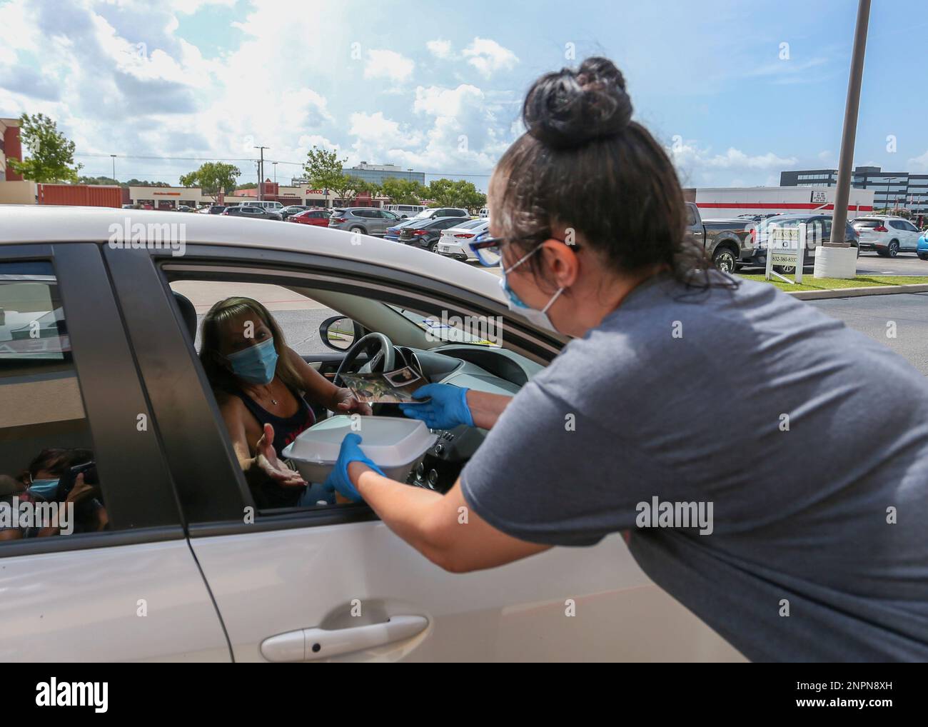 HOUSTON, TX - AUGUST 09: Wael's Mediterranean Cuisine server hands a carryout box to a drive-thru diner on August 09, 2020, in Houston, TX. The restaurant is donating hundreds of free meals to first responders and the unemployed affected by the coronavirus (COVID-19) pandemic. (Photo by Leslie Plaza Johnson/Icon Sportswire) (Icon Sportswire via AP Images) Stockfoto