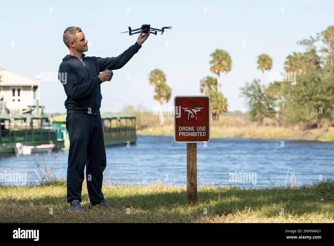 Der Mann wird seinen Quadcopter in kein Drohnengebiet fliegen. Betreiber, der sein UAS rechtswidrig im State Park in der Nähe des Schilds für Beschränkungen verwendet. Stockfoto