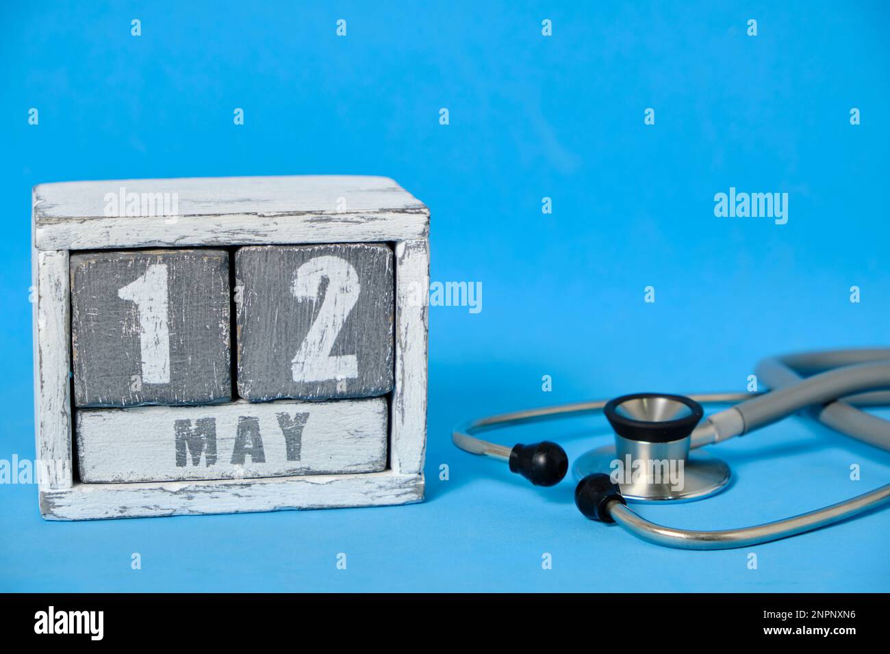 Mai 12, Holzkalender und Stethoskop auf blauem Hintergrund. Konzept für den Tag der Krankenschwester Stockfoto