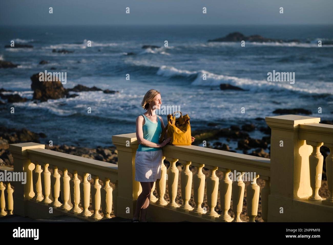 Eine Frau mit Rucksack steht an der Atlantikküste, Portugal. Stockfoto