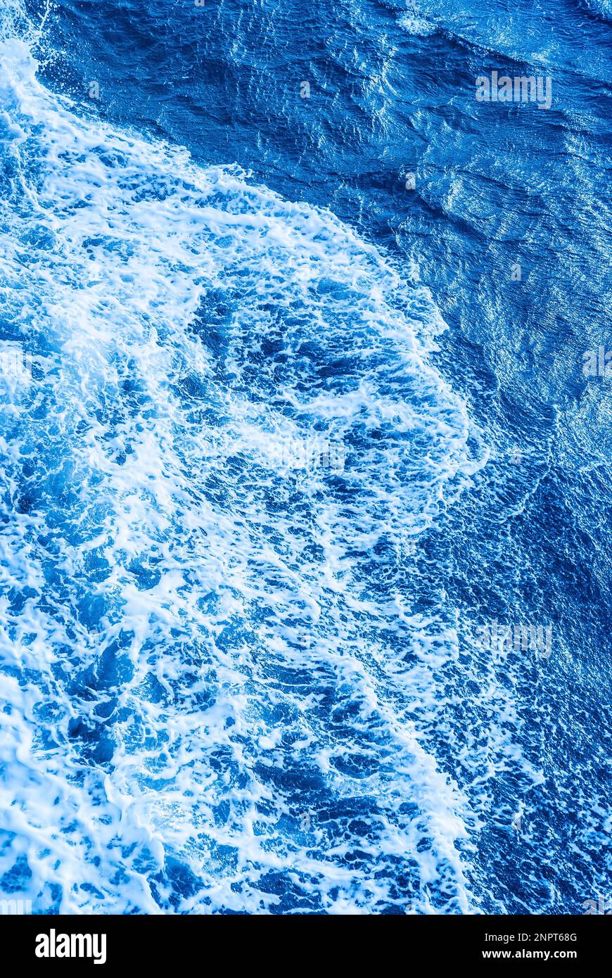 Ozeanblaue Oberfläche mit Schaumstoff und Wellen vertikal. Stockfoto