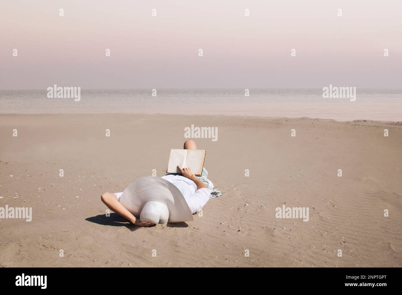Eine Frau in der Entspannung liest ein Buch am Strand Stockfoto