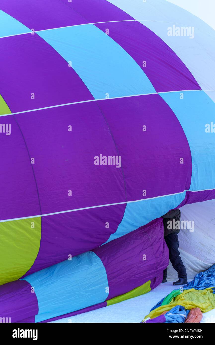 Ein Mann, der von einem Heißluftballon begraben wurde. Aufgenommen beim 42. Internationalen Ballonfestival in Chateau D'Oex im Januar 2023. Stockfoto