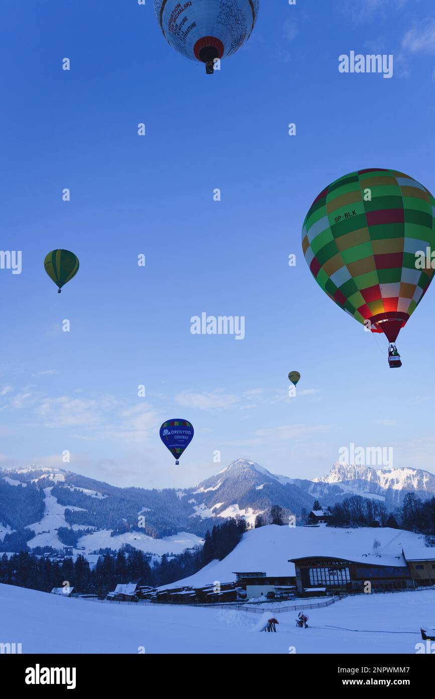 Ballons, die über den schweizer alpen hängen. Aufgenommen beim 42. Internationalen Ballonfestival in Chateau D'Oex im Januar 2023. Stockfoto