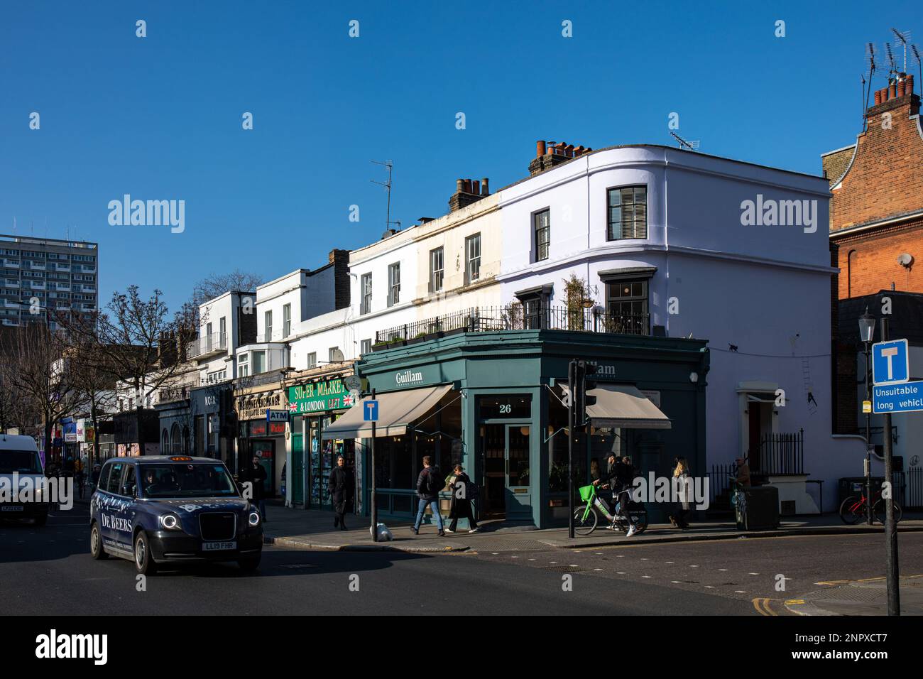 Weißes dreistöckiges Gebäude am Notting Hill Gate vor klarem blauen Himmel Notting Hill District in London, England Stockfoto