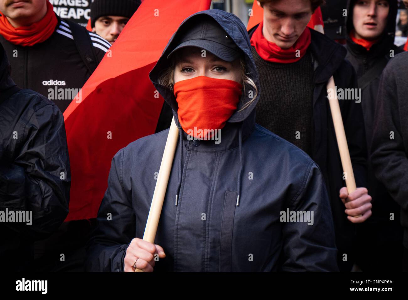 London, Großbritannien. 25. Februar 2023. Ein protestteilnehmer mit kommunistischer Flagge schließt sich dem demonstrationsmarsch an. Nach dem ersten Jahrestag des Krieges zwischen Russland und der Ukraine versammelten sich Protestgruppen in Central London und marschierten zum Trafalgar Square, um Frieden in der Ukraine und im Iran zu fordern. Kredit: SOPA Images Limited/Alamy Live News Stockfoto