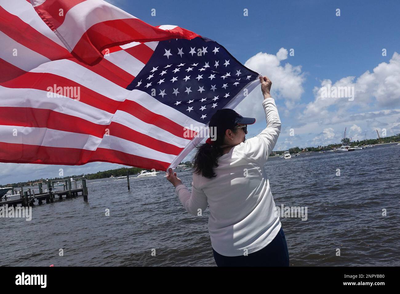 Rosa Median waves a United States flag to boats that were part of a Flag Day and President Donald Trump birthday flotilla at Mar-A-Lago in Palm Beach, Fla., Sunday, June 14, 2020. (Joe Cavaretta/South Florida Sun-Sentinel via AP) Stockfoto