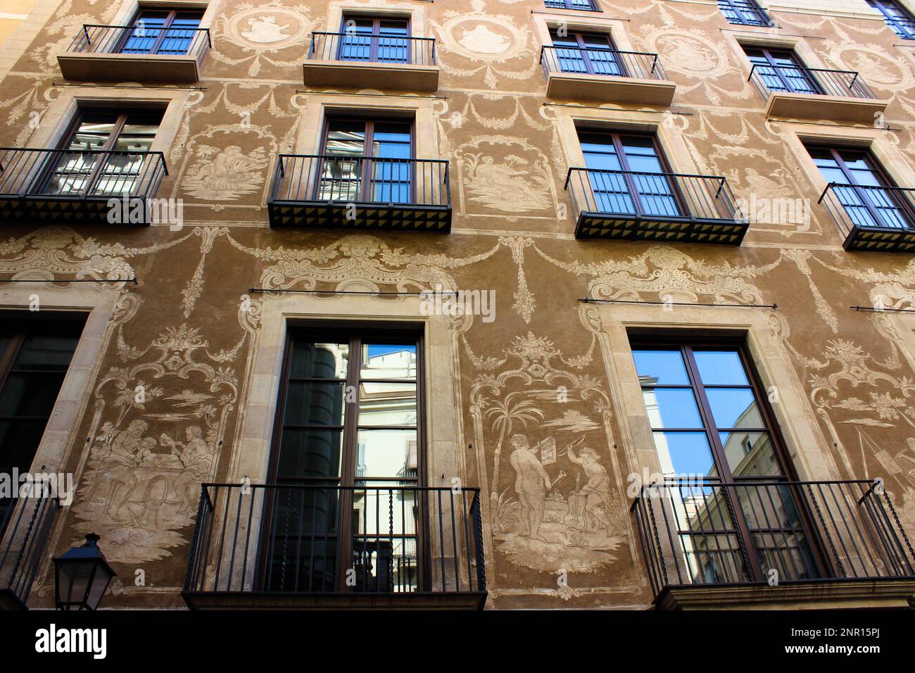 Ein altes Gebäude mit großen Fensterreihen und braunen Wänden, die mit Zeichnungen mittelalterlicher Alltagsszenen und Requisiten geschmückt sind. Stockfoto